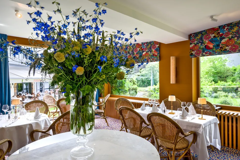 Table dressée avec un grand bouquet de fleurs dans la salle lumineuse du Barbizon