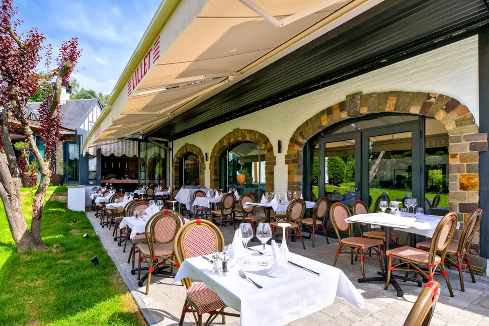 Terrasse ensoleillée du Barbizon avec tables dressées face au jardin