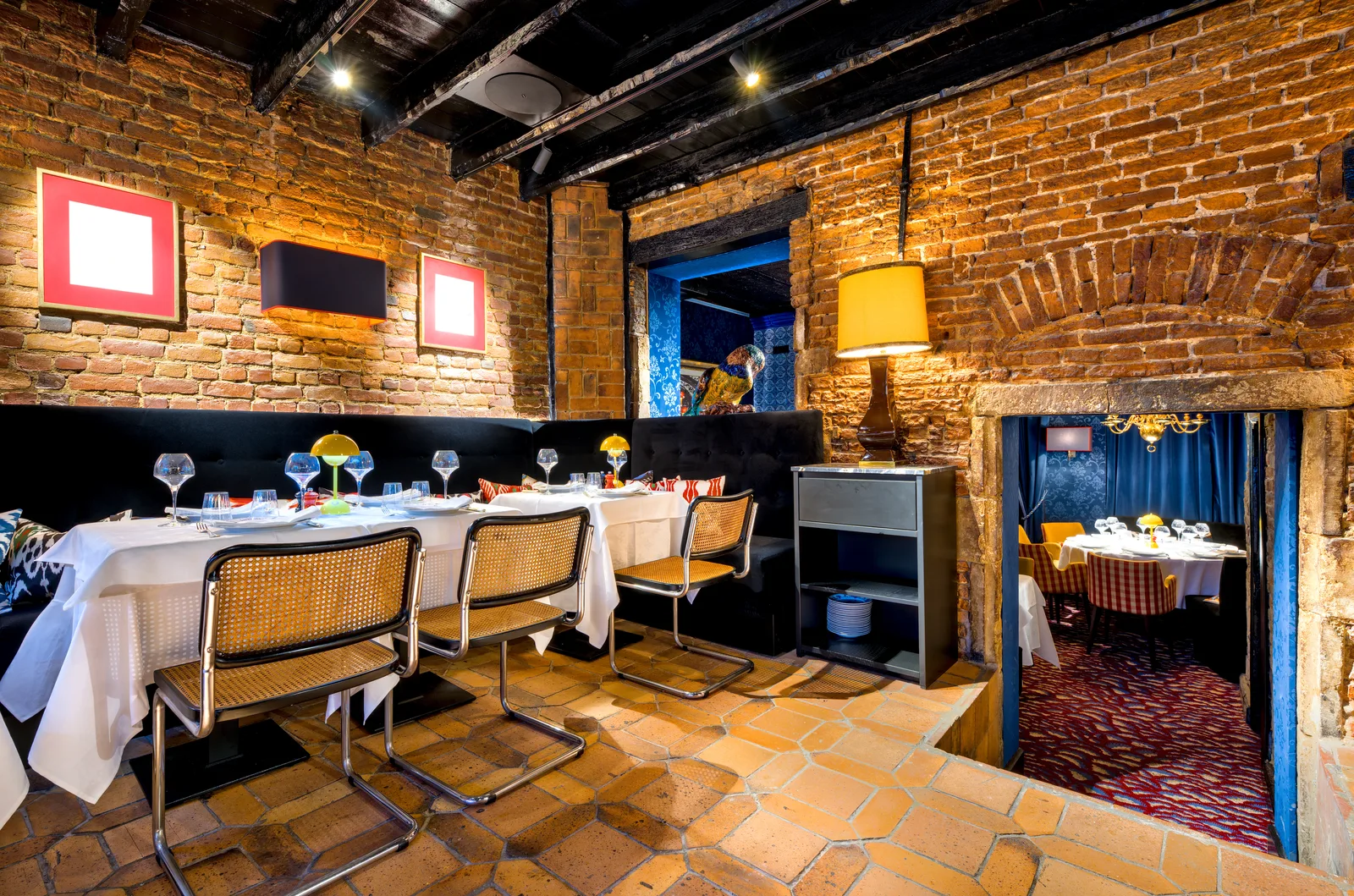 Salle du restaurant aux murs de briques et tables dressées